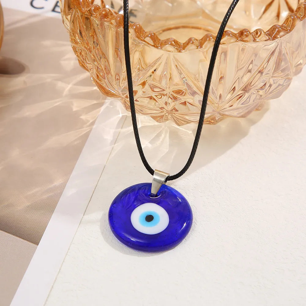 Collier avec pendentif œil bleu, symbole de protection contre le mauvais œil, sur cordon noir.