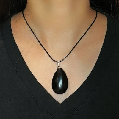 Collier avec pendentif en forme de goutte d'obsidienne noire sur un cordon noir, porté par une femme.