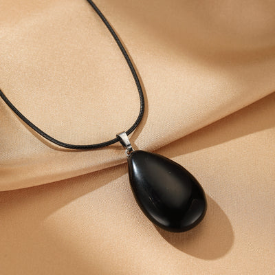 Collier avec pendentif en forme de larme en obsidienne noire sur un cordon noir.