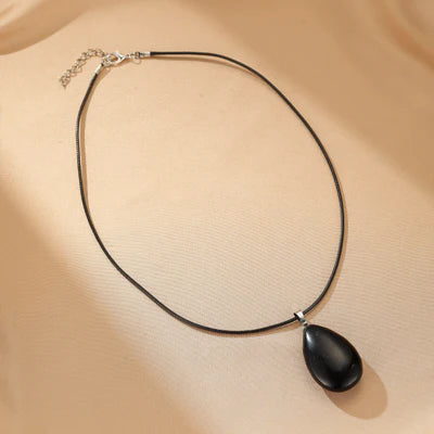 Collier ras-de-cou avec un pendentif en forme de goutte d'obsidienne noire polie, monté sur un cordon fin.