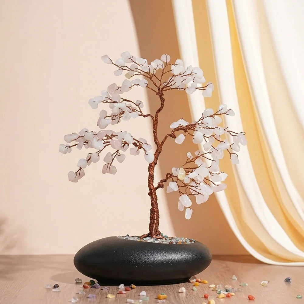 Arbre de Vie artisanal en quartz rose "Douceur Amoureuse" avec des feuilles en pierres roses et blanches, monté sur un tronc en fil de cuivre torsadé, le tout dans un pot noir ovale rempli de gravier coloré.