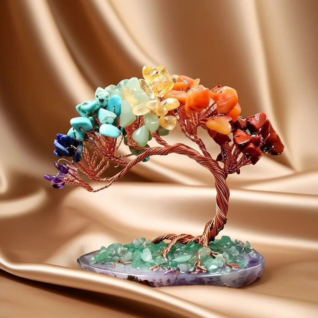 Arbre de vie décoratif avec pierres colorées des 7 chakras et un bracelet assorti sur un fond satiné.