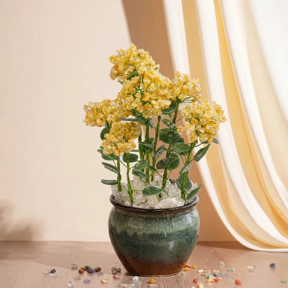 Arbre de vie en citrine avec des fleurs jaunes vives et des feuilles vertes, dans un pot en céramique vert foncé, décoré de cristaux blancs.