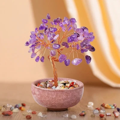 Arbre de vie décoratif avec des pierres d'améthyste violettes et un tronc en fil de cuivre torsadé, posé dans un pot rose rempli de cailloux colorés.