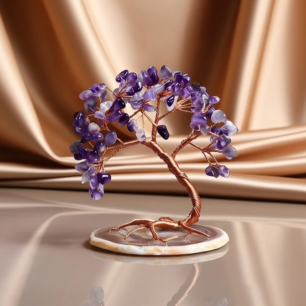 Arbre de vie décoratif en améthyste avec des branches en cuivre et une base en agate, sur un fond de tissu satiné doré.