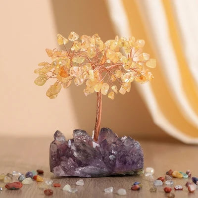 Arbre de Vie "Symphonie Lumineuse" décoratif avec des feuilles en citrine et une base en améthyste brute, posé sur une surface en bois avec des pierres éparpillées.